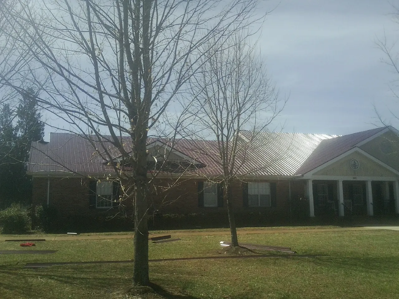 Red metal roof on a brick building seen from the front lawn in Sabattus