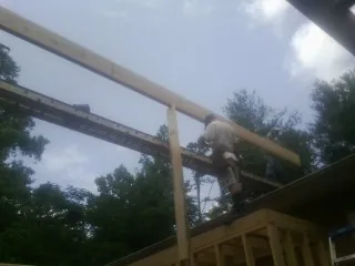 Carpenter setting a ridge beam over a new addition frame — Ice Dam Removal by Roofing Brothers in Sabattus