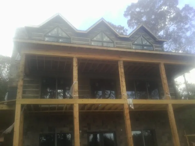 Dormers and porch framing on a large log home under construction — Roof Coating work by our crew in Sabattus