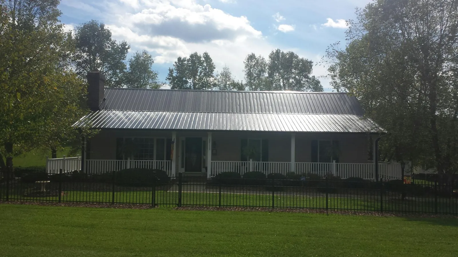 Gray metal roof on a brick ranch with a full width front porch — Gutter Guard Installation work by our crew in Sabattus