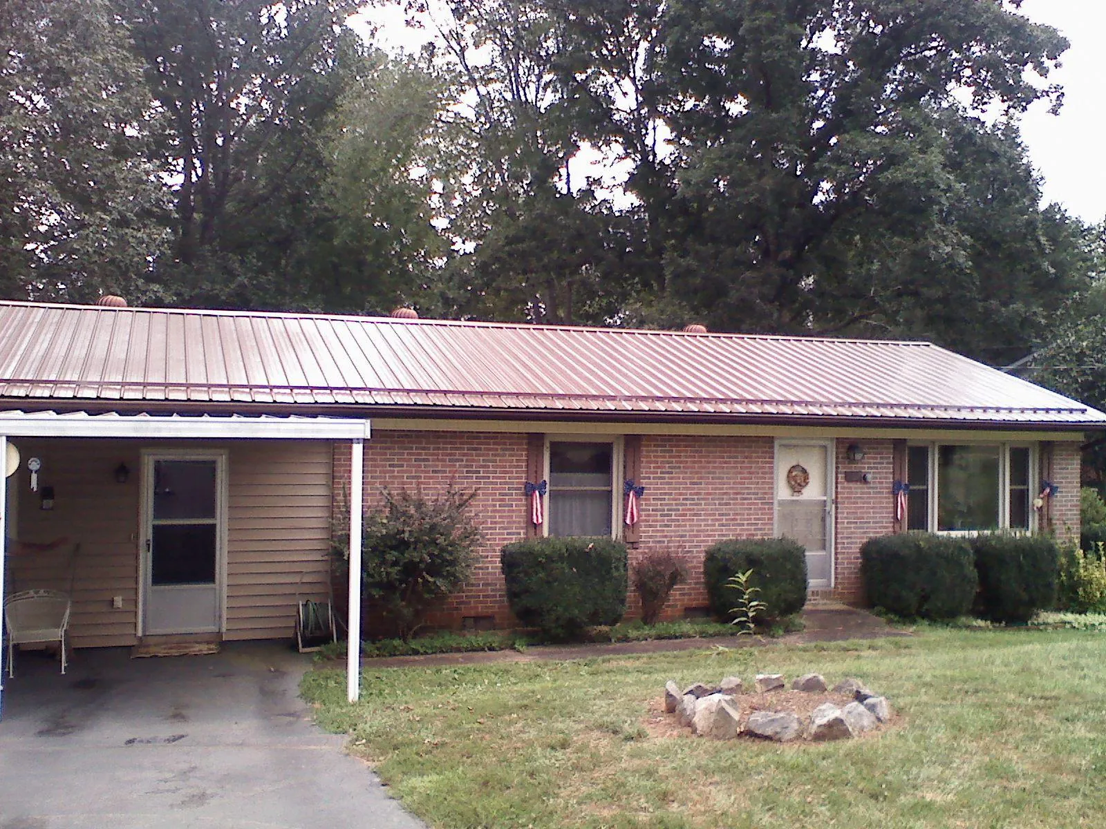 Bronze metal roof and carport on a brick ranch home — Roof Repair work by our crew in Sabattus