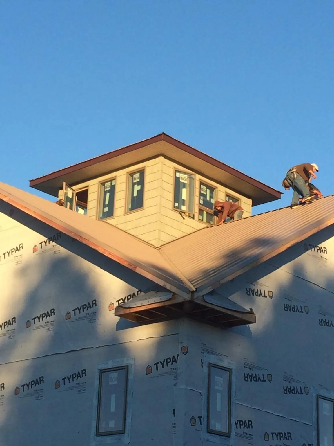 Roofers working around a rooftop cupola on a new metal roof at sunset — Roof Waterproofing in Sabattus by Roofing Brothers